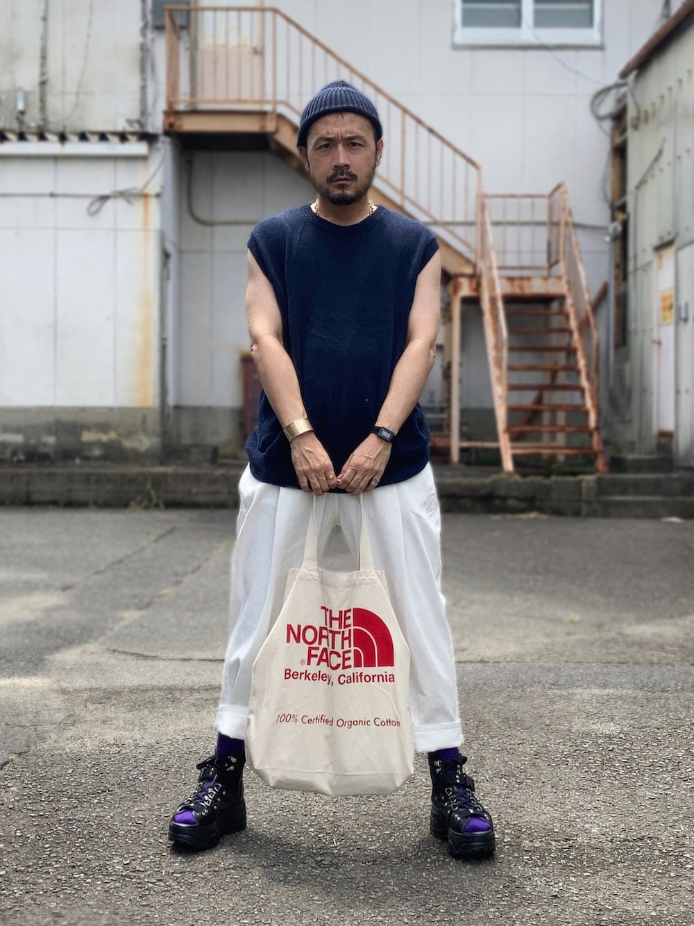 ブルー系のベスト、ホワイト系のスラックス、ブラック系のサンダルを着用したメンズの夏コーディネートの2枚目の写真