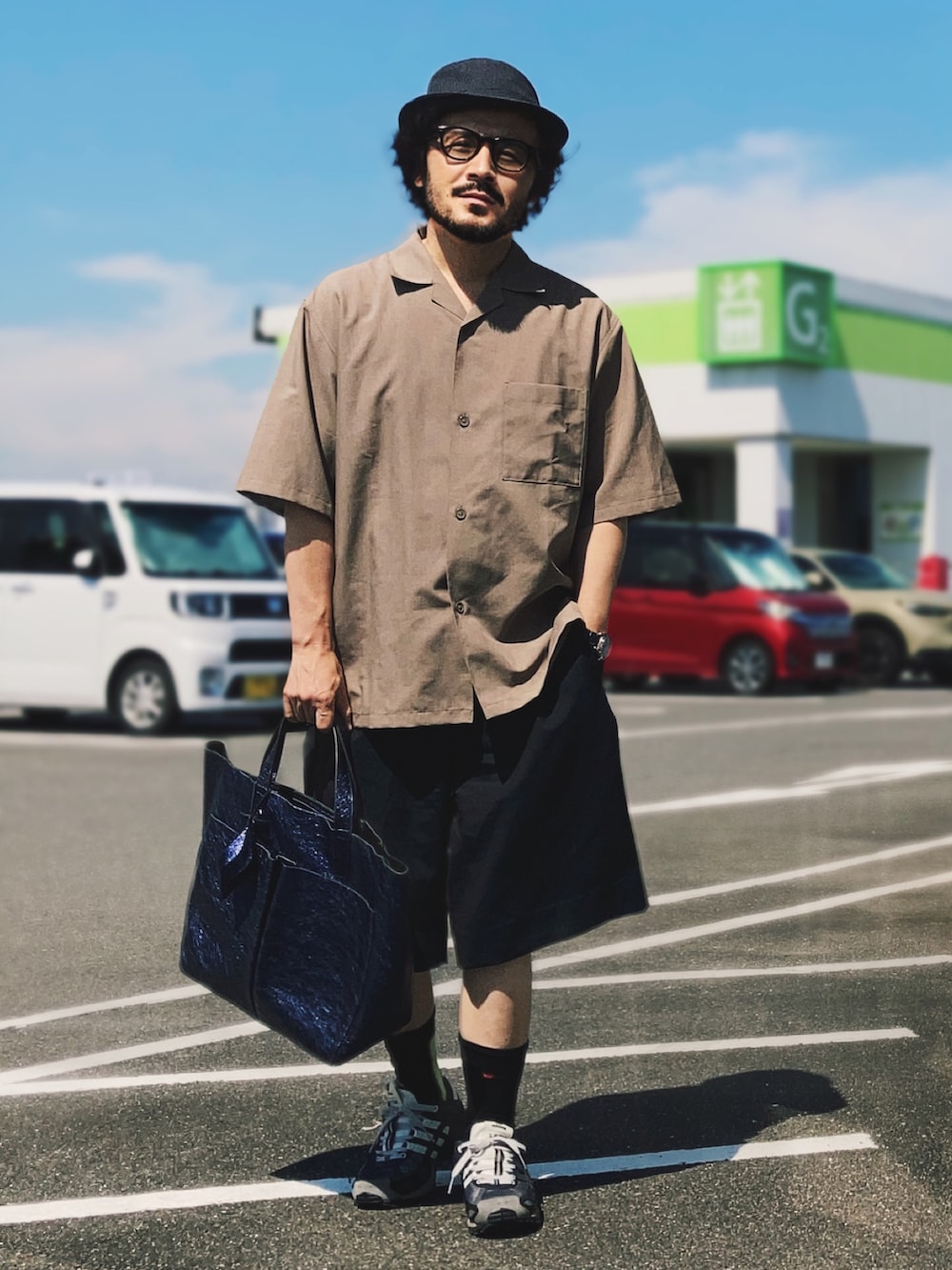 ブラック系のスニーカー、ブラウン系のシャツ/ブラウス、ブルー系のスラックスを着用したメンズの夏コーディネートの2枚目の写真