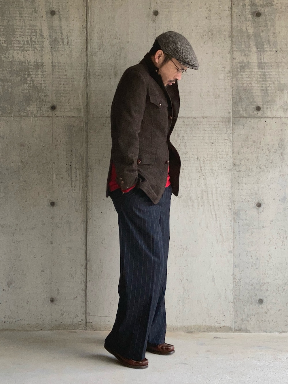 レッド系のニット/セーター、ブラウン系のテーラードジャケット、ブルー系のスラックスを着用したメンズの冬コーディネートの2枚目の写真