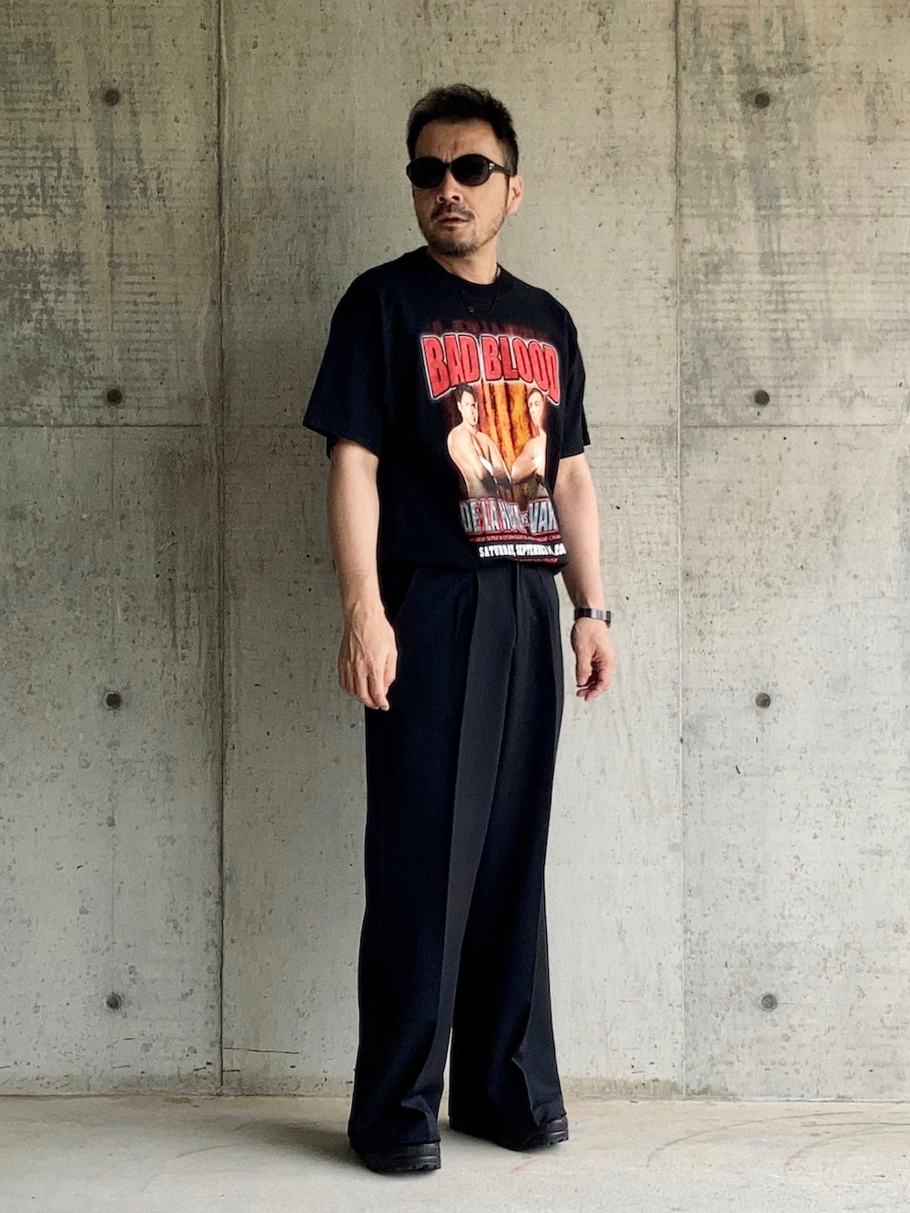 ブラック系のTシャツ/カットソー、ブラック系のスラックス、ブラック系のサンダルを着用したメンズの夏コーディネートの2枚目の写真