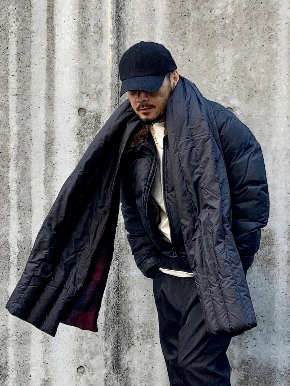 ベージュ系のTシャツ/カットソー、ブラック系のダウンジャケット/コート、ブラック系のスラックスを着用したメンズの冬コーディネートの4枚目の写真