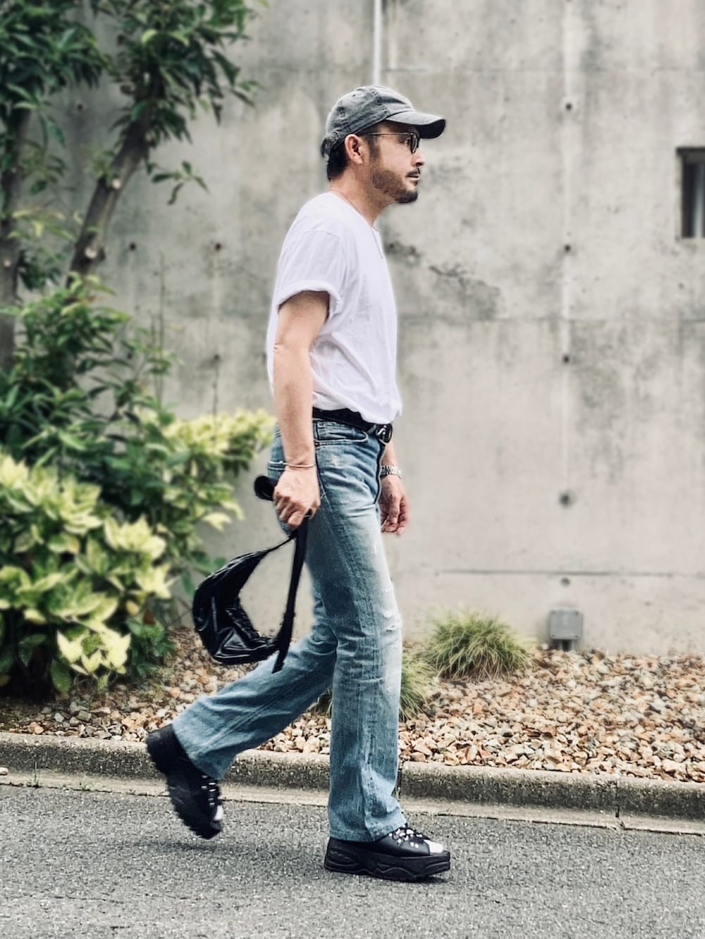 ホワイト系のTシャツ/カットソー、ブルー系のデニムパンツ、ブラック系のサンダルを着用したメンズの夏コーディネートの2枚目の写真