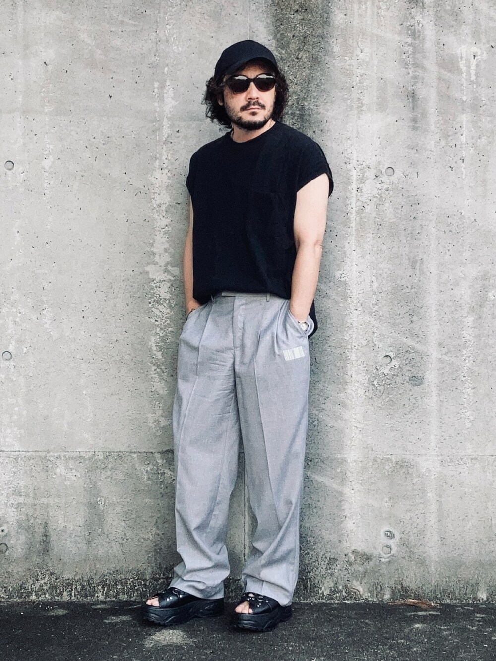 グレー系のスラックス、ブラック系のその他トップス、ブラック系のサンダルを着用したメンズの夏コーディネートの3枚目の写真
