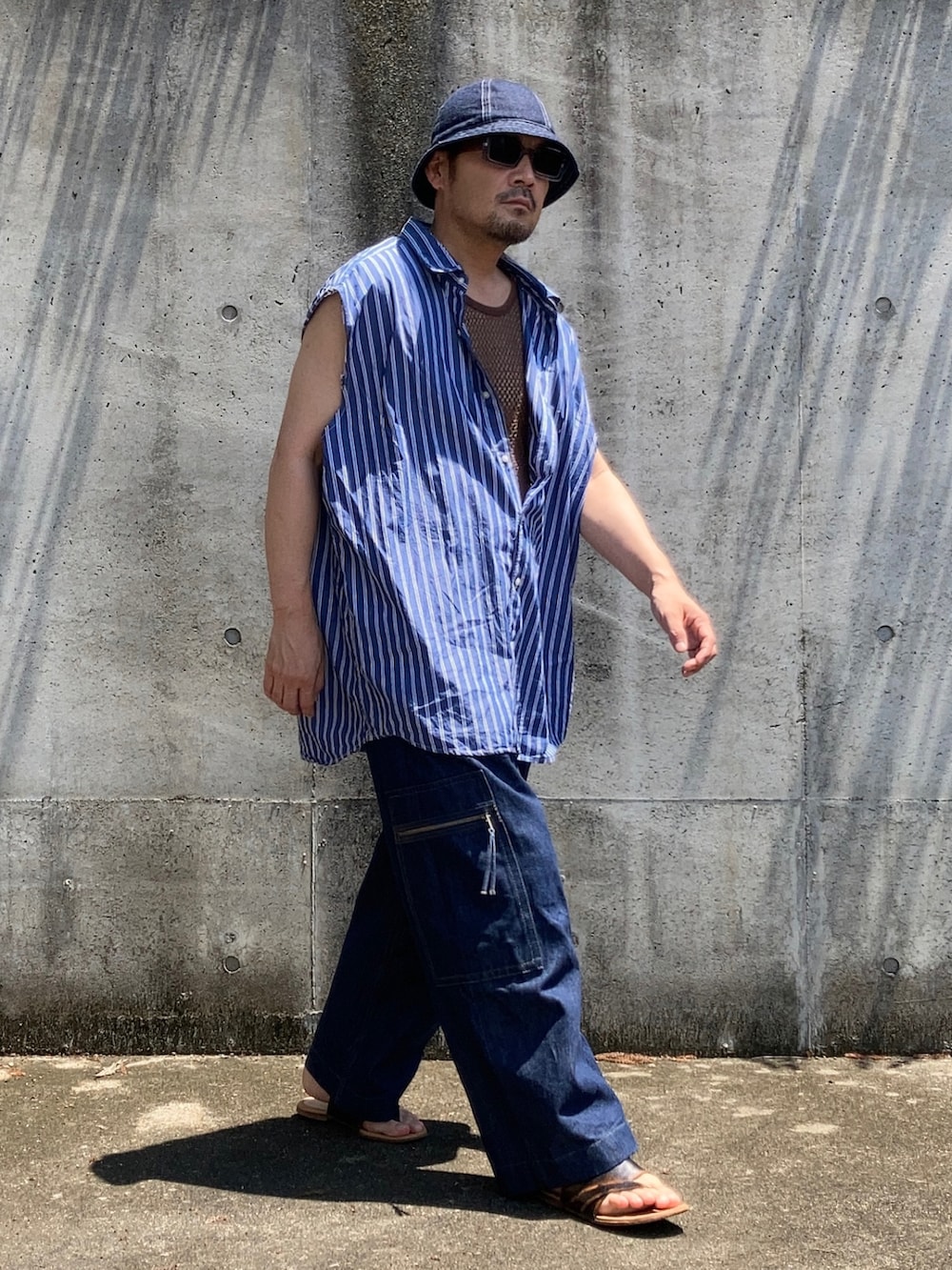 ブルー系のデニムパンツ、ブルー系のシャツ/ブラウス、ブラウン系のタンクトップを着用したメンズの夏コーディネートの2枚目の写真