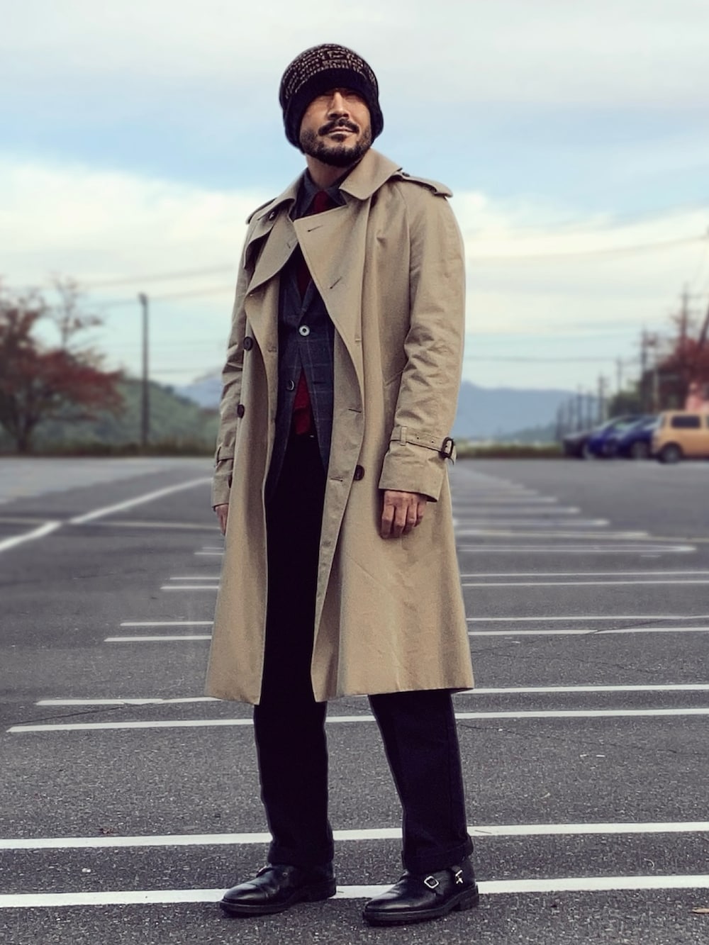 ベージュ系のトレンチコート、グレー系のテーラードジャケット、ブラック系のドレスシューズを着用したメンズの秋コーディネートの3枚目の写真