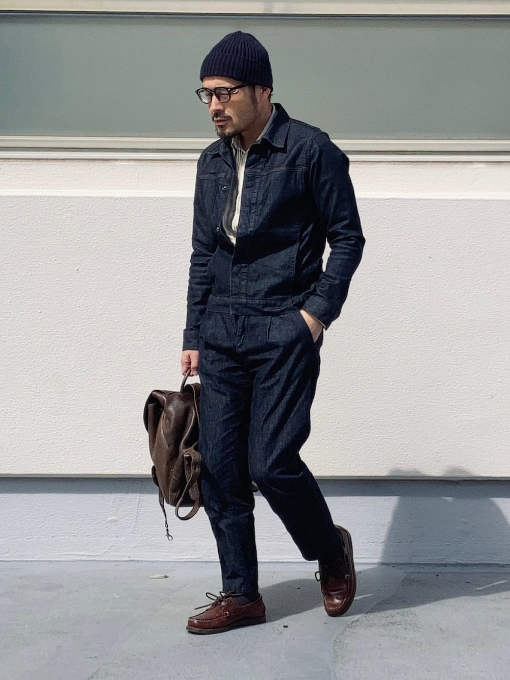 ブラウン系のバックパック/リュック、ブルー系のデニムジャケット、ブルー系のデニムパンツを着用したメンズの春コーディネートの2枚目の写真