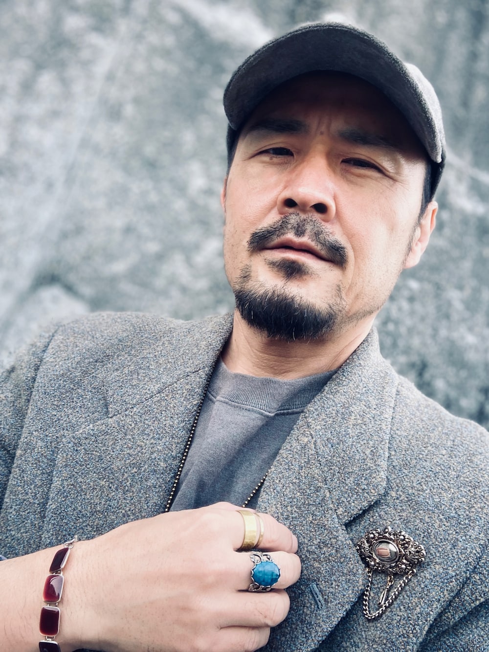 グレー系のテーラードジャケット、グリーン系のニット/セーター、ホワイト系のデニムパンツを着用したメンズの春コーディネートの4枚目の写真