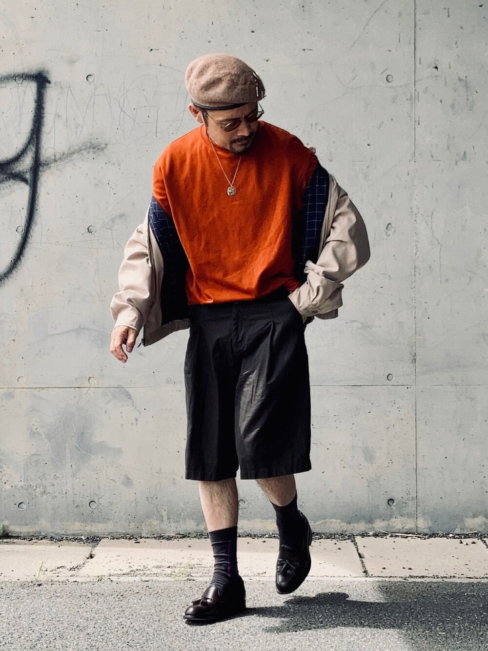 オレンジ系のTシャツ/カットソー、ベージュ系のブルゾン、ブラウン系のパンツを着用したメンズの秋コーディネートの2枚目の写真