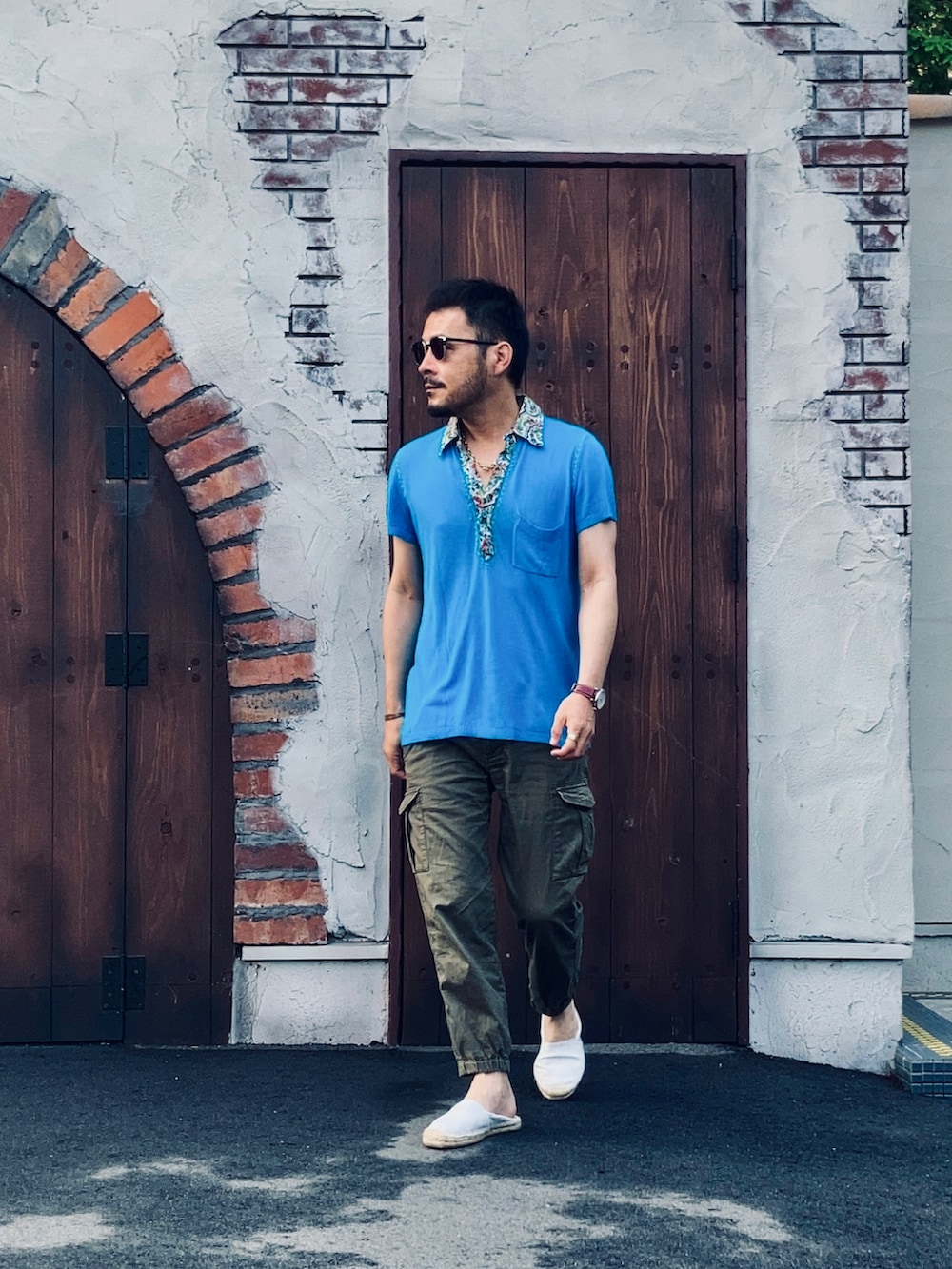 グリーン系のパンツ、ホワイト系のスリッポン、ブルー系のポロシャツを着用したメンズの夏コーディネートの3枚目の写真