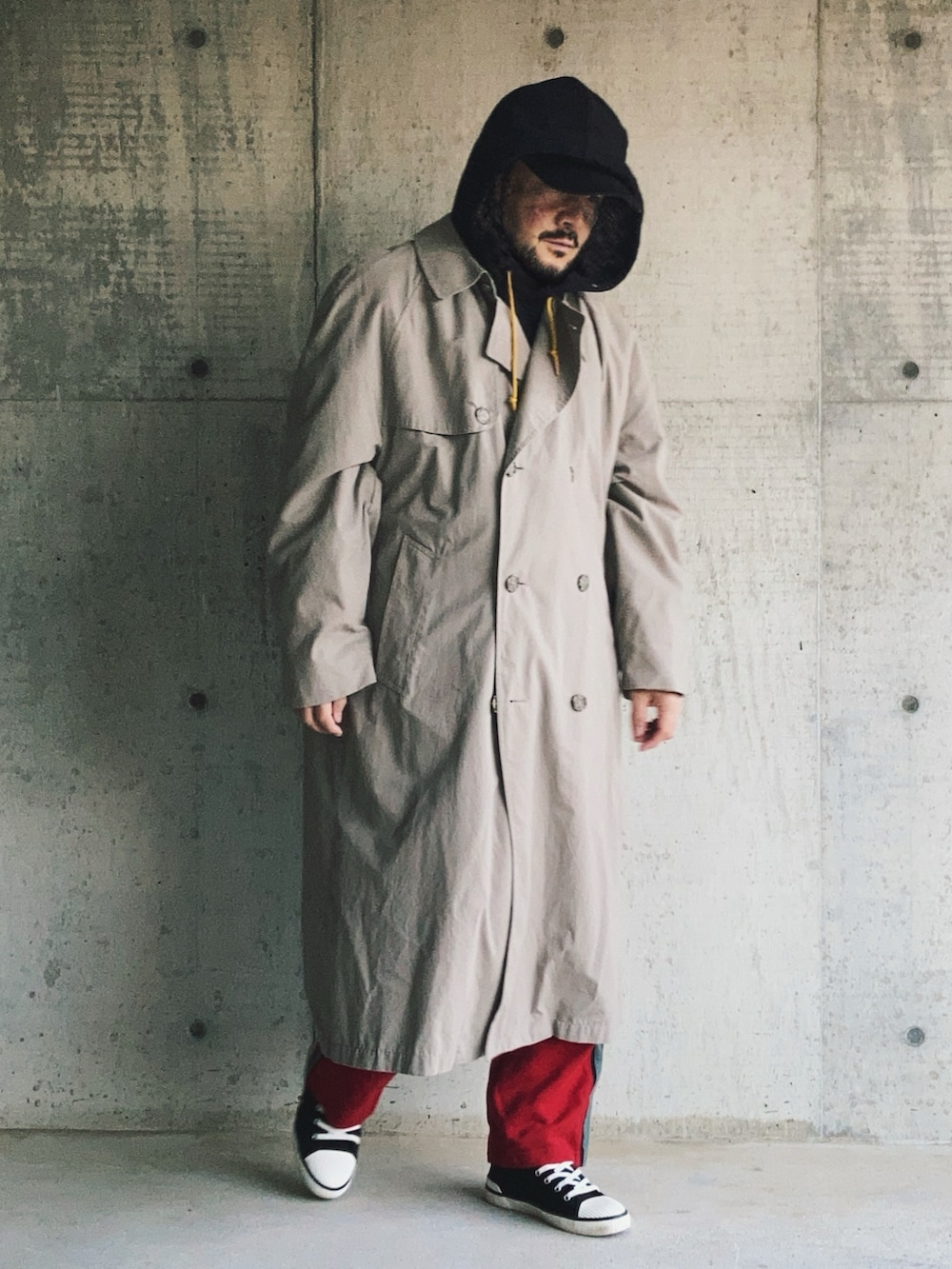 ブラック系のパーカー、ベージュ系のトレンチコート、レッド系のスウェットパンツを着用したメンズの秋コーディネートの4枚目の写真