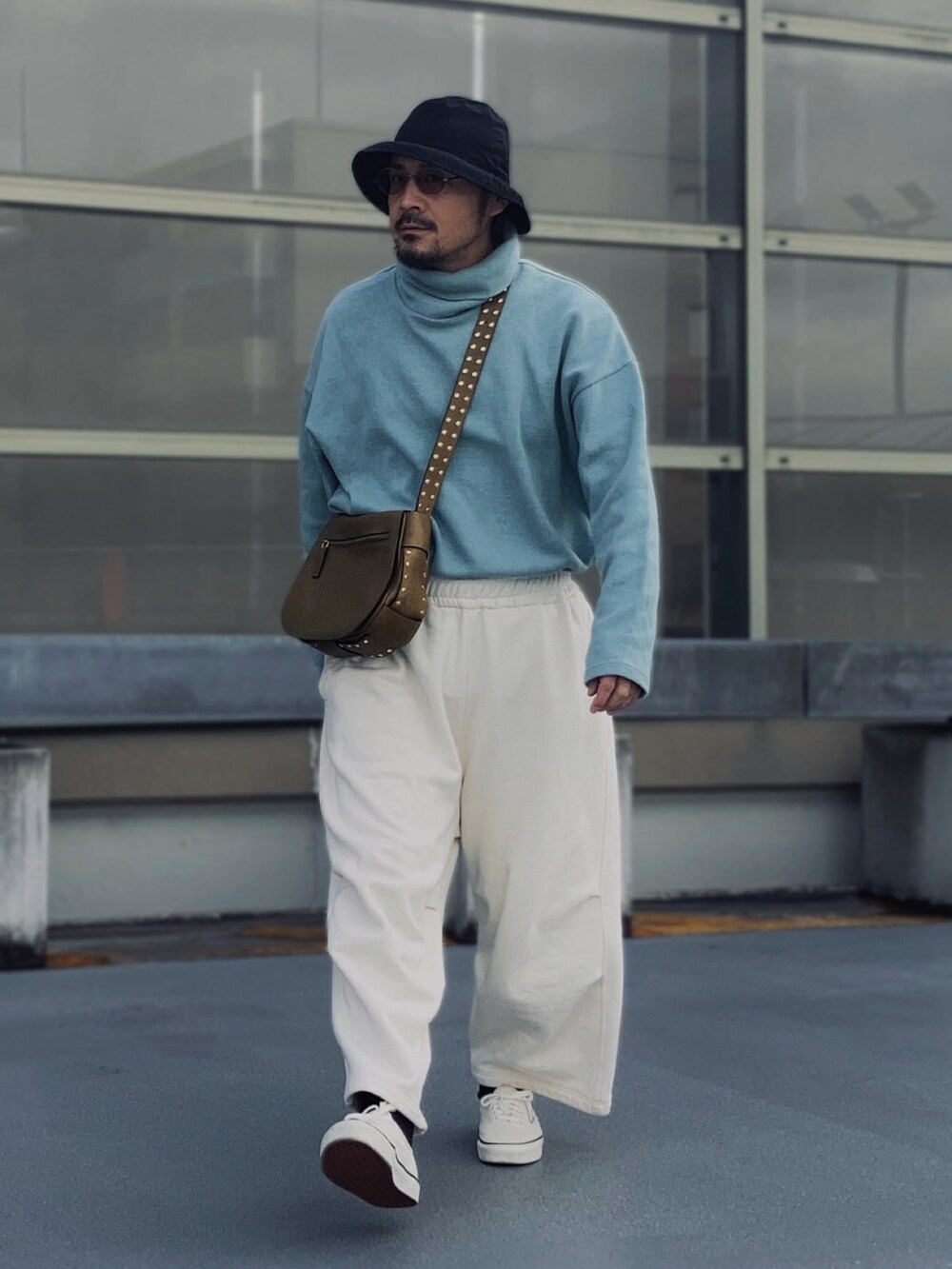 グレー系のスウェットパンツ、ブルー系のニット/セーター、ホワイト系のスニーカーを着用したメンズの春コーディネートの2枚目の写真