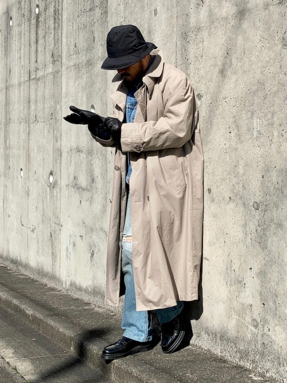 グレー系のニット/セーター、ブルー系のデニムジャケット、ベージュ系のトレンチコートを着用したメンズの冬コーディネートの2枚目の写真