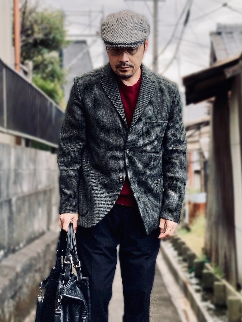 レッド系のニット/セーター、グレー系のテーラードジャケット、ブラック系のスラックスを着用したメンズの秋コーディネートの3枚目の写真