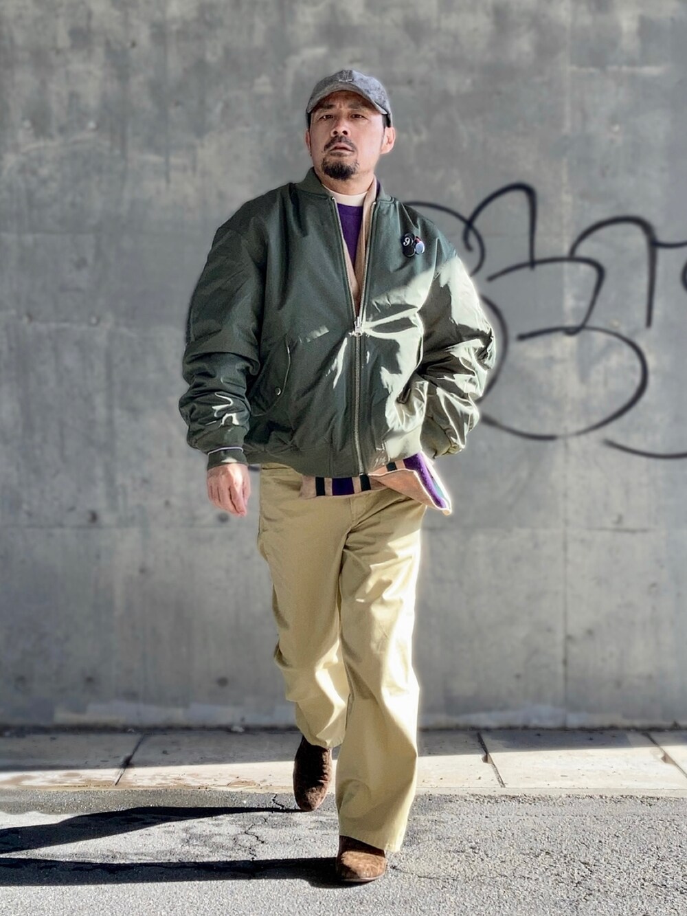 ベージュ系のTシャツ/カットソー、パープル系のスウェット、グリーン系のMA-1を着用したメンズの冬コーディネートの3枚目の写真