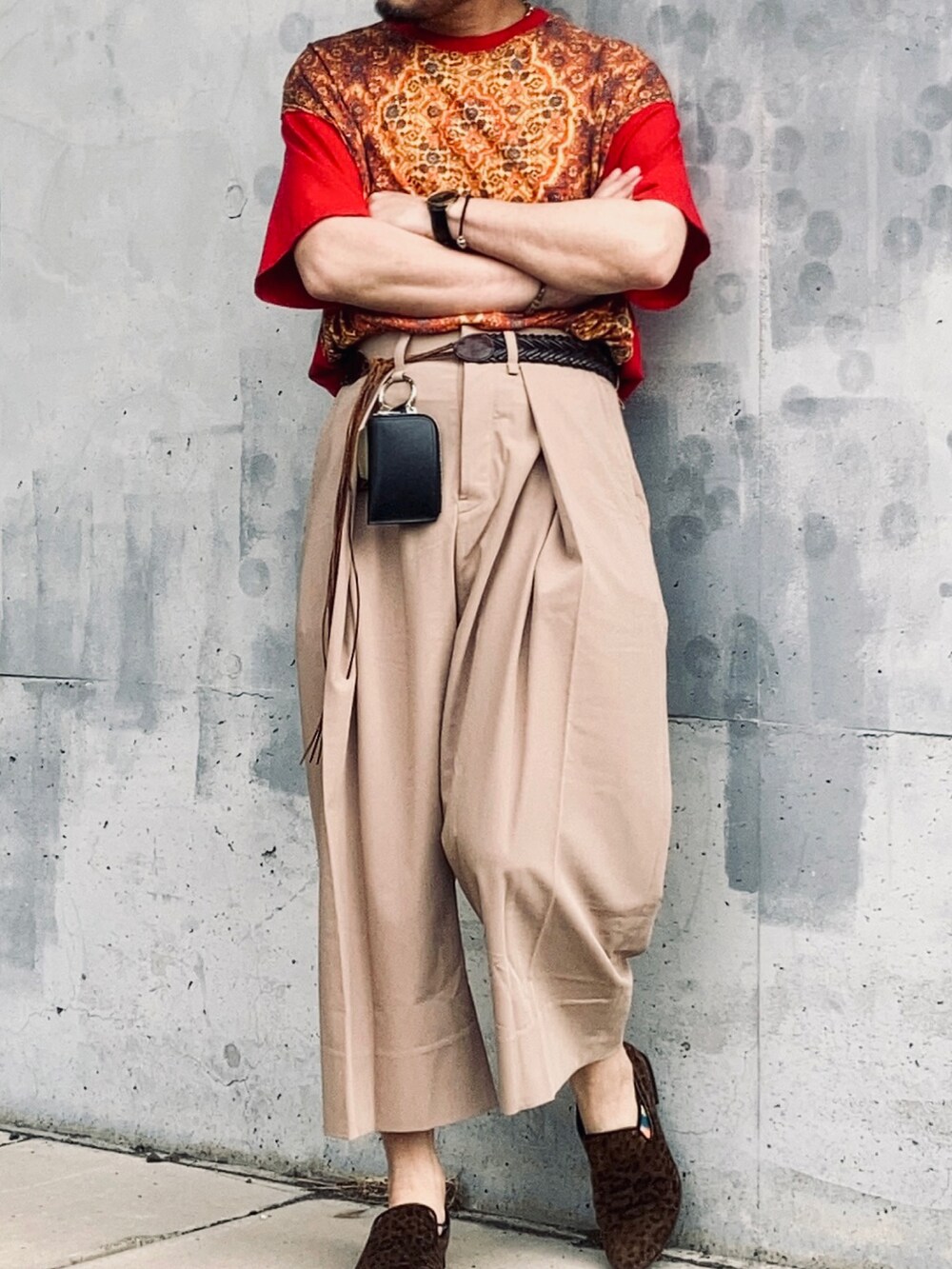 レッド系のTシャツ/カットソー、ベージュ系のスラックス、ブラウン系のスリッポンを着用したメンズの春コーディネートの4枚目の写真