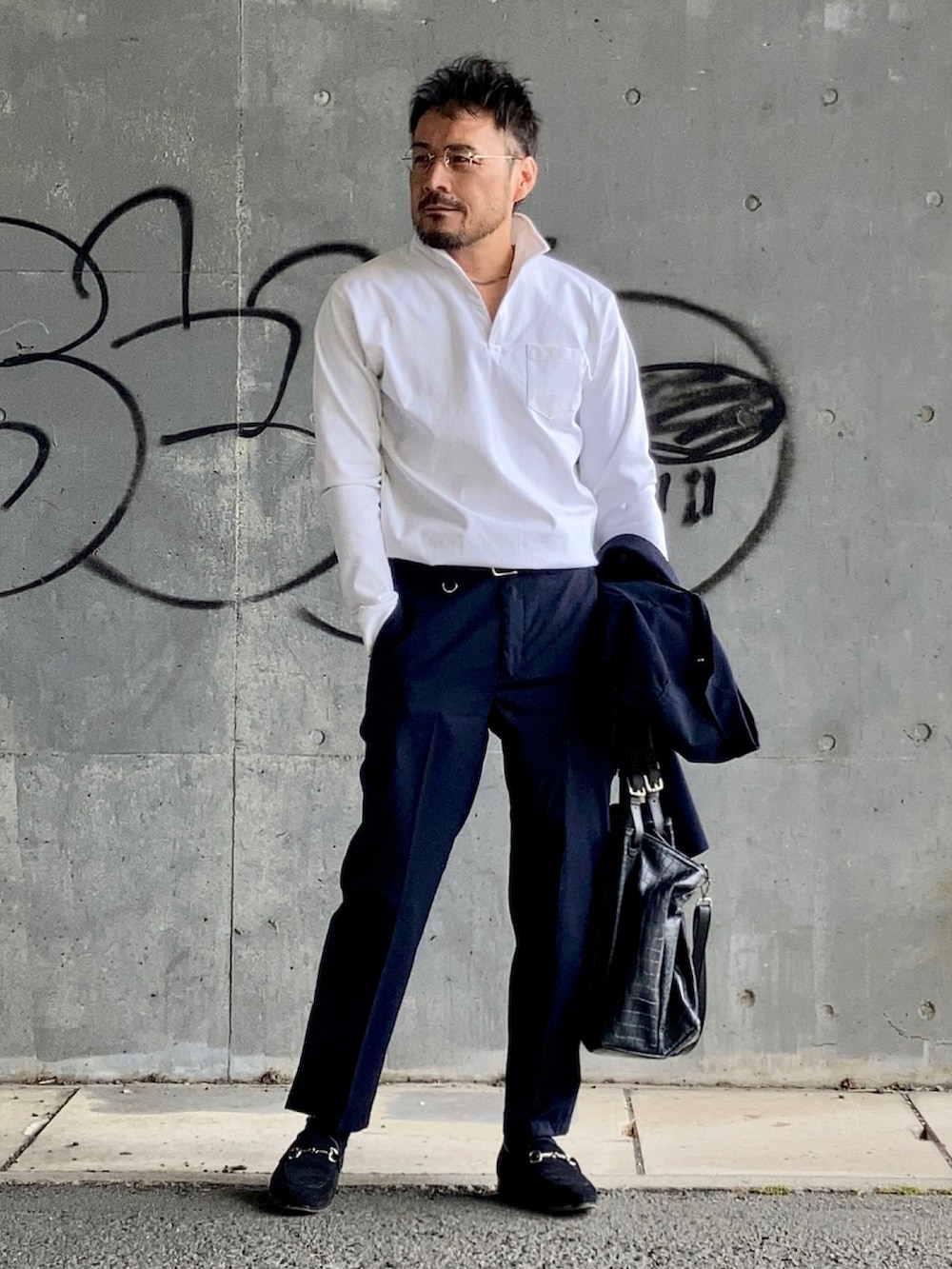 ホワイト系のポロシャツ、ブルー系のスラックス、ブラック系のローファーを着用したメンズの春コーディネートの2枚目の写真