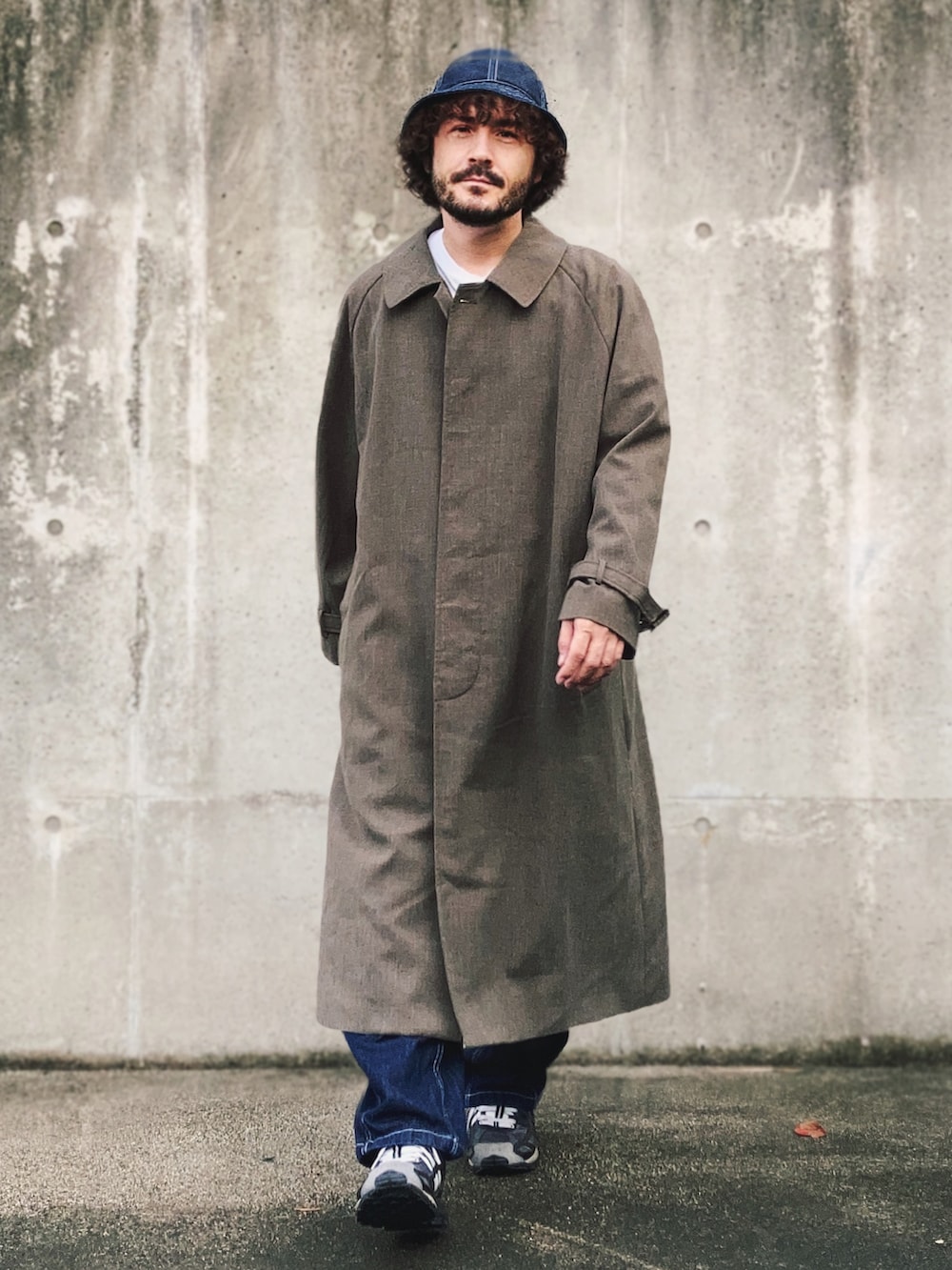 グレー系のステンカラーコート、ホワイト系のTシャツ/カットソー、ブルー系のデニムパンツを着用したメンズの秋コーディネートの3枚目の写真