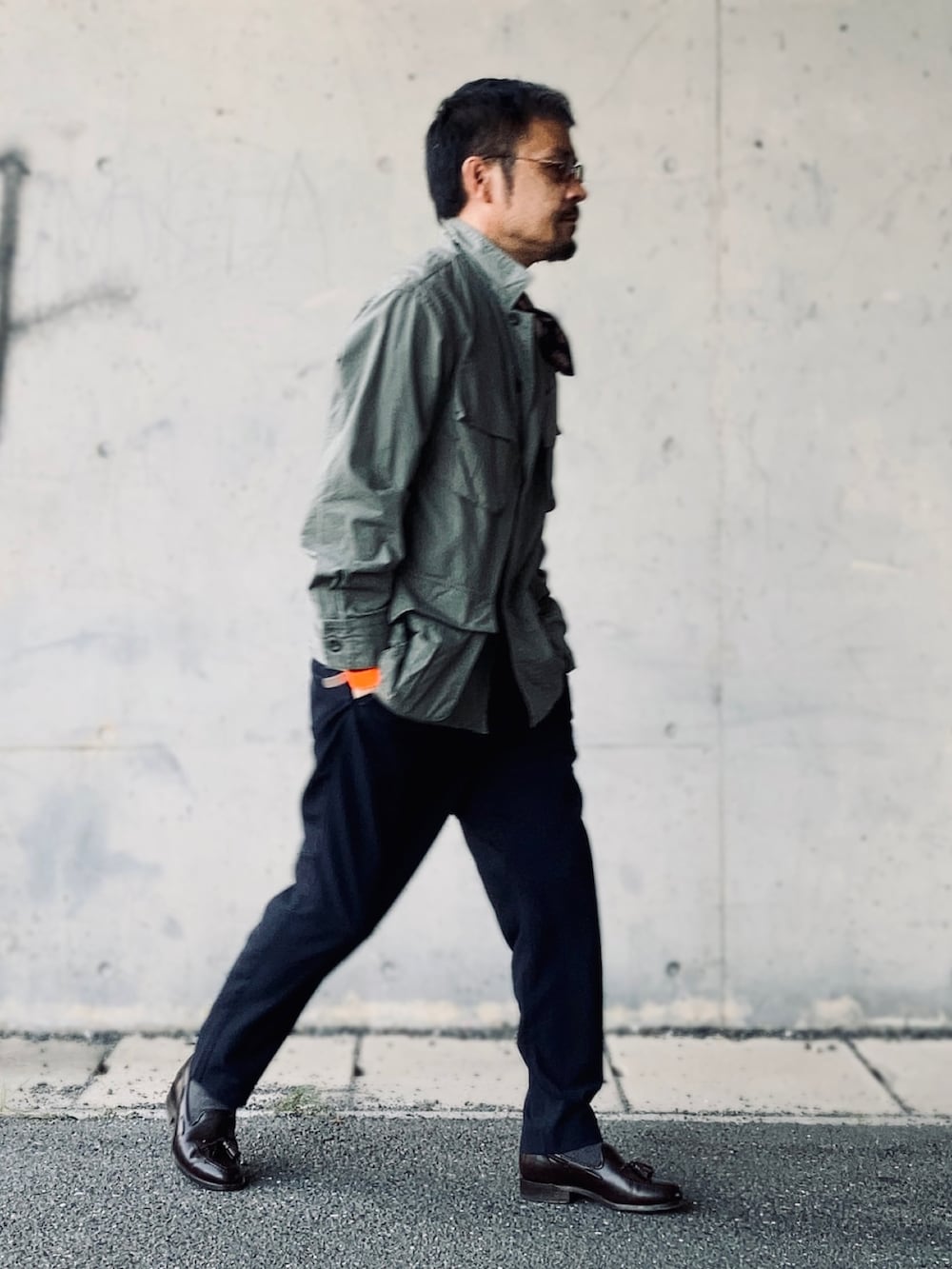 グリーン系のミリタリージャケット、ブルー系のスラックス、ブラウン系のローファーを着用したメンズの秋コーディネートの2枚目の写真