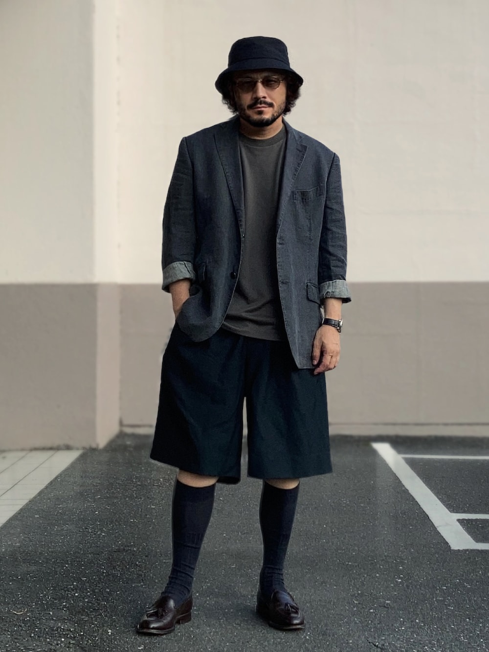 グレー系のテーラードジャケット、ブルー系のスラックス、ブラウン系のローファーを着用したメンズの夏コーディネートの2枚目の写真