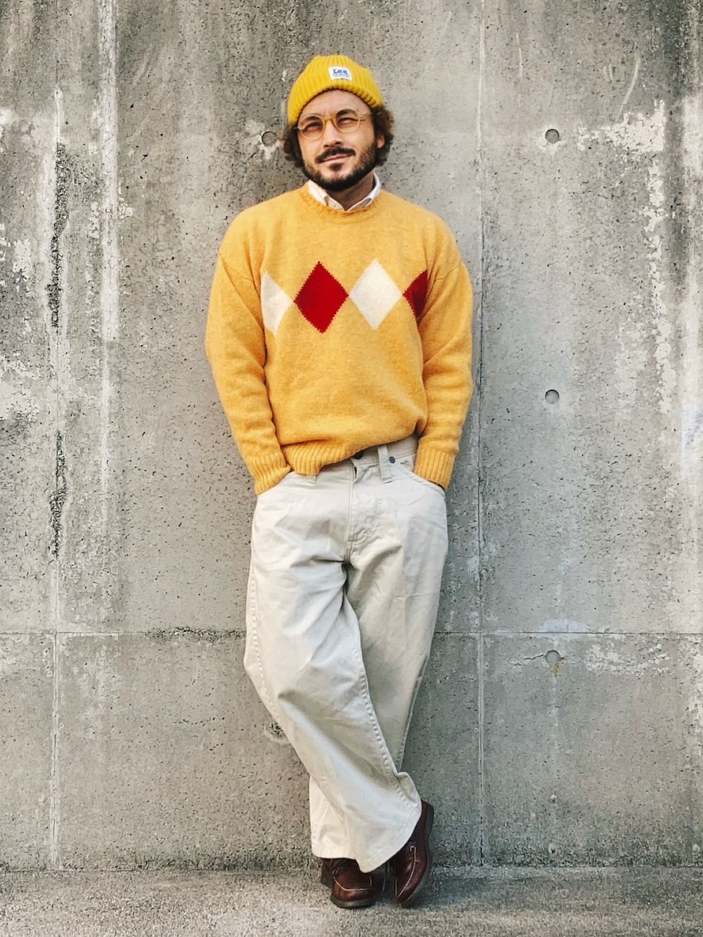 イエロー系のニット/セーター、ホワイト系のデニムパンツ、ブラウン系のモカシン/デッキシューズを着用したメンズの冬コーディネートの2枚目の写真