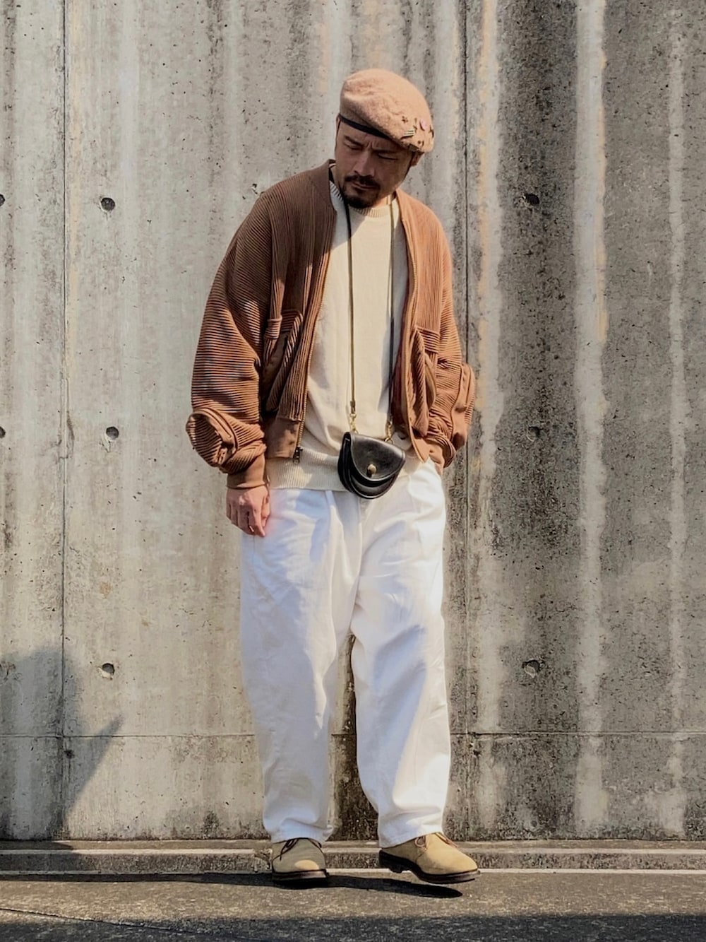 ベージュ系のニット/セーター、ブラウン系のMA-1、ホワイト系のスラックスを着用したメンズの春コーディネートの2枚目の写真