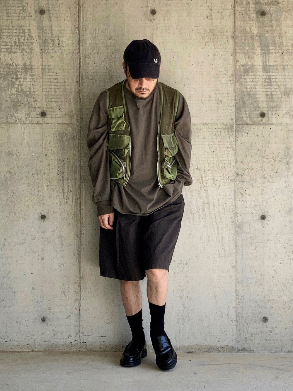 グリーン系のTシャツ/カットソー、グリーン系のベスト、ブラウン系のパンツを着用したメンズの秋コーディネートの3枚目の写真