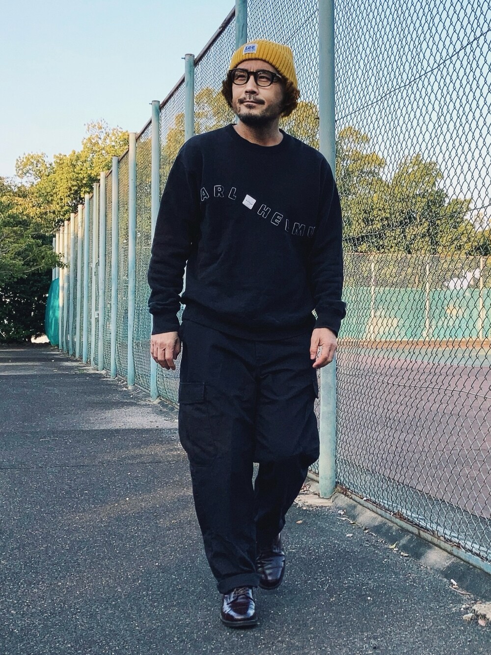 ブラック系のスウェット、ブラック系のカーゴパンツ、レッド系のドレスシューズを着用したメンズの春コーディネートの2枚目の写真