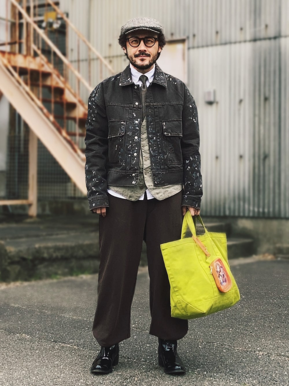 ブラウン系のデニムジャケット、グリーン系のベスト、ブラウン系のスウェットパンツを着用したメンズの春コーディネートの3枚目の写真