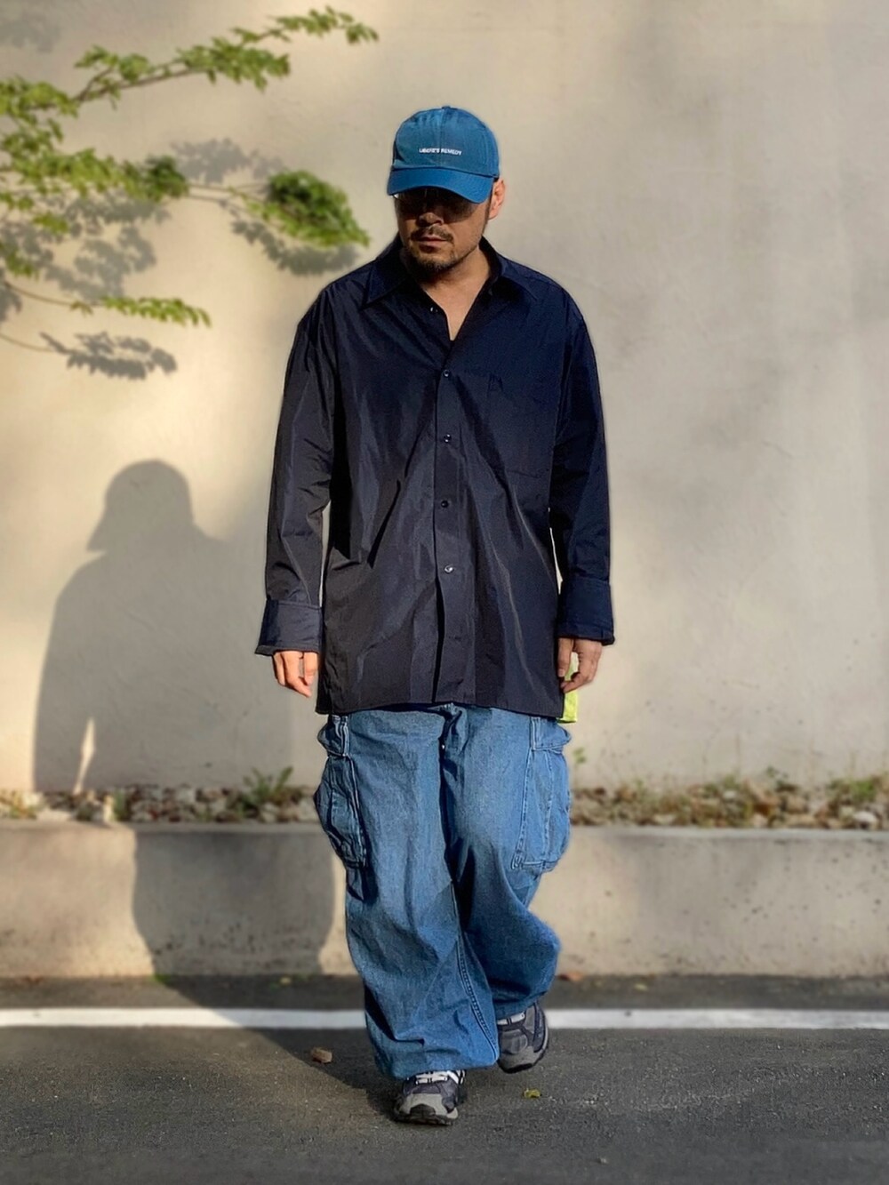 ブラック系のシャツ/ブラウス、ブルー系のカーゴパンツ、ブラック系のスニーカーを着用したメンズの春コーディネートの2枚目の写真