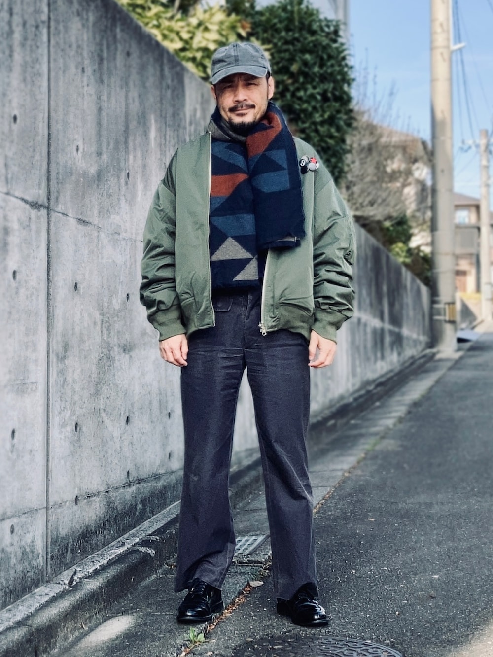 グリーン系のMA-1、グレー系のスラックス、ブラック系のドレスシューズを着用したメンズの冬コーディネートの2枚目の写真