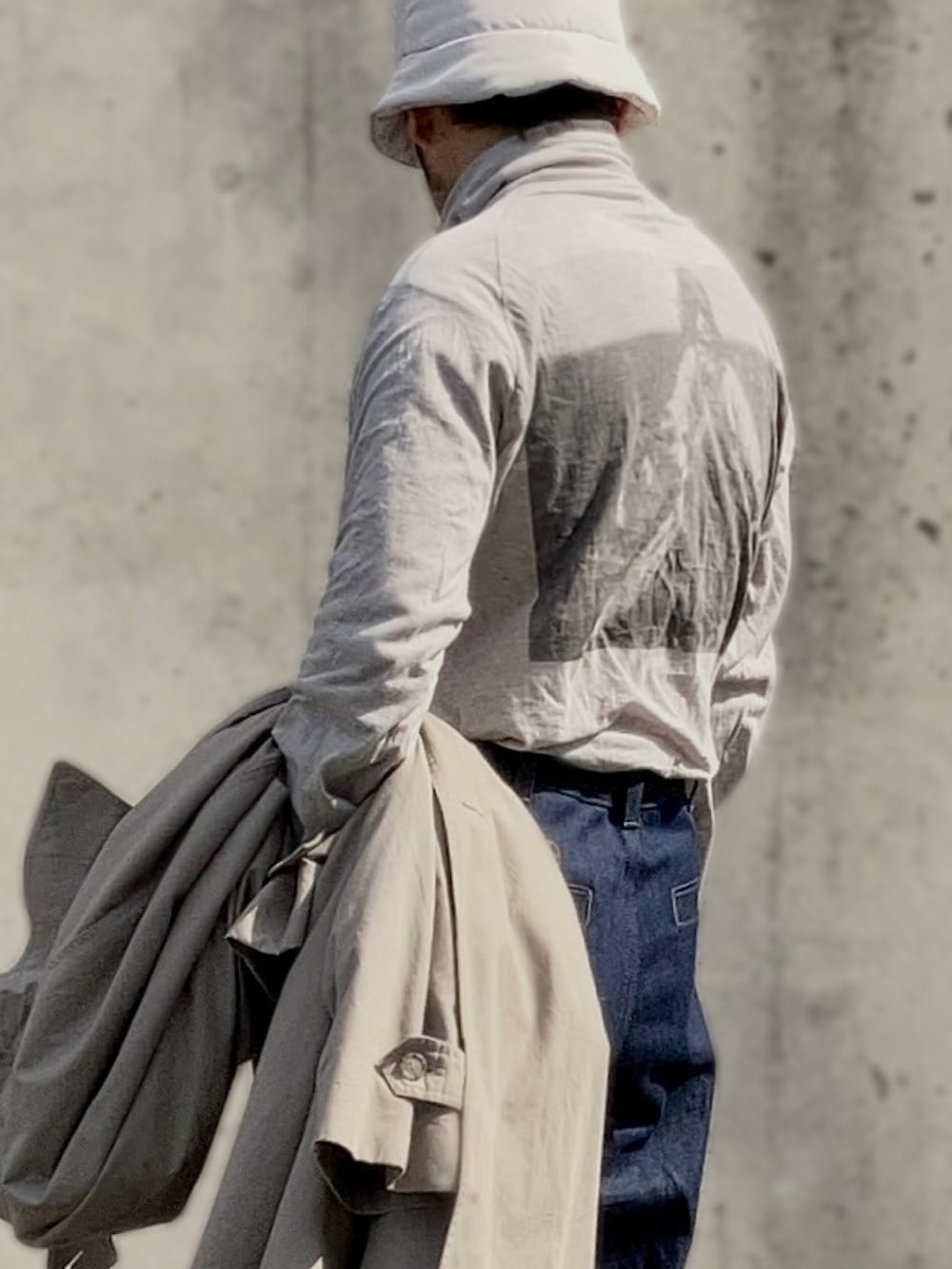 グレー系のTシャツ/カットソー、ベージュ系のトレンチコート、ブルー系のデニムパンツを着用したメンズの春コーディネートの3枚目の写真