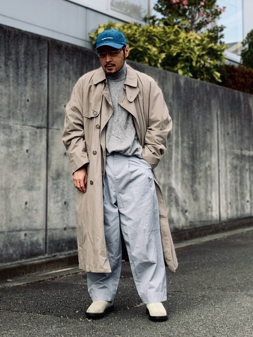 グレー系のニット/セーター、ベージュ系のトレンチコート、グレー系のパンツを着用したメンズの冬コーディネートの2枚目の写真