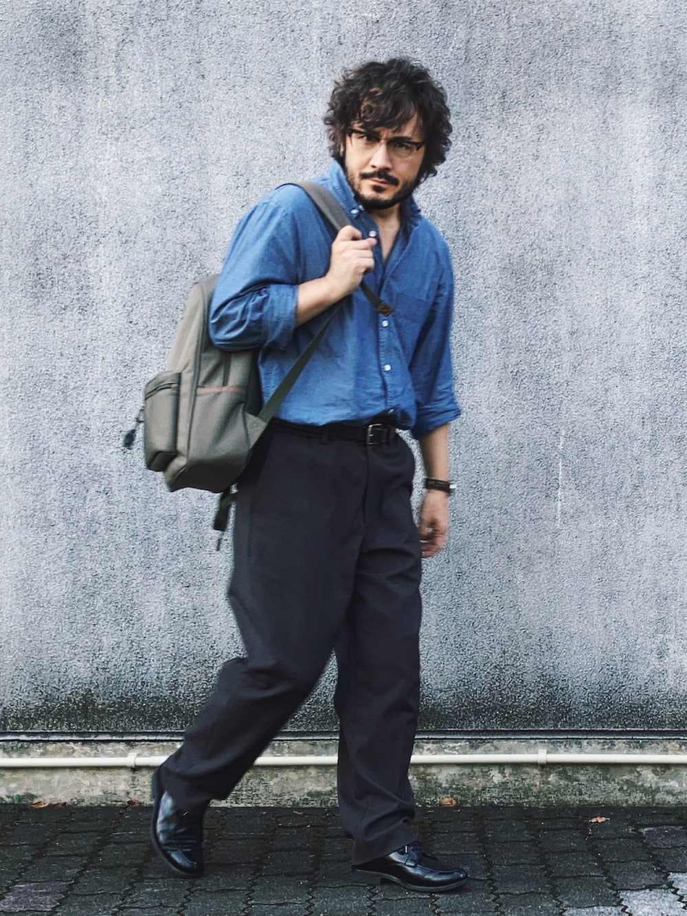 グレー系のバックパック/リュック、ブラック系のドレスシューズ、ブルー系のシャツ/ブラウスを着用したメンズの秋コーディネートの2枚目の写真