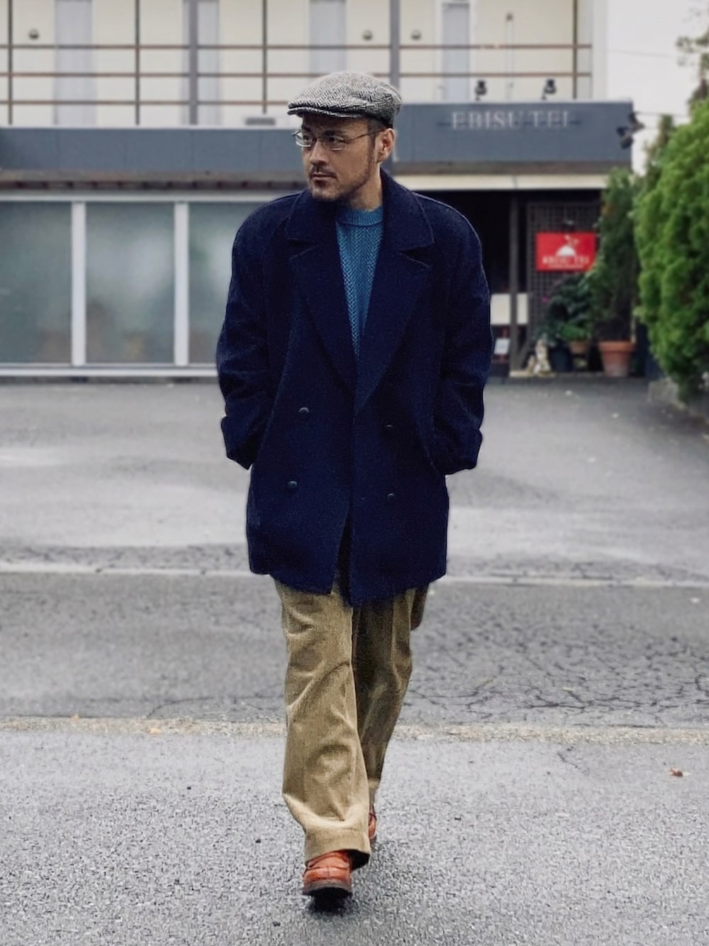 ブルー系のニット/セーター、ブルー系のピーコート、ゴールド系のスラックスを着用したメンズの秋コーディネートの2枚目の写真