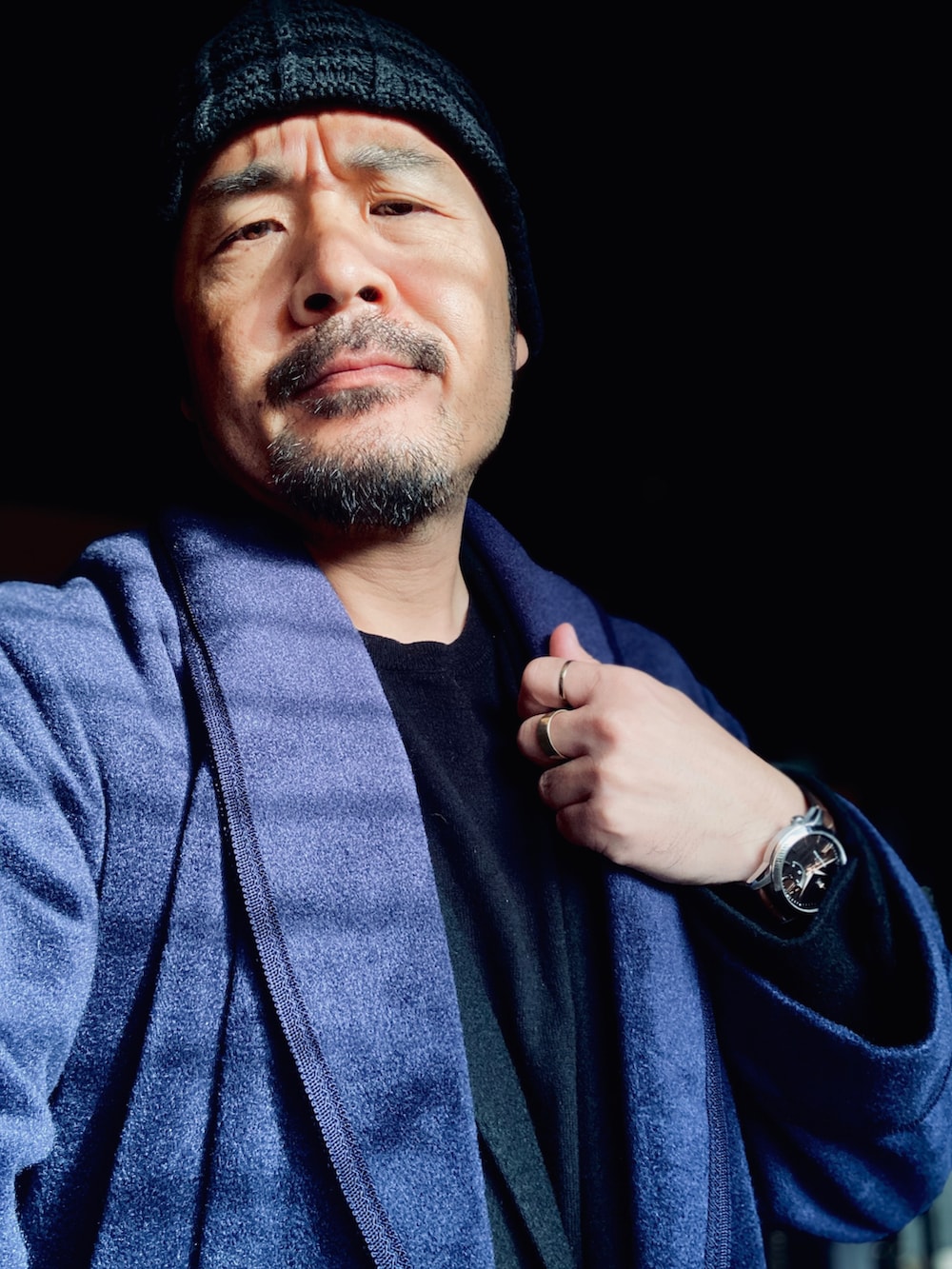 ブラック系のニット/セーター、ブラック系のテーラードジャケット、ブルー系のその他アウターを着用したメンズの秋コーディネートの4枚目の写真