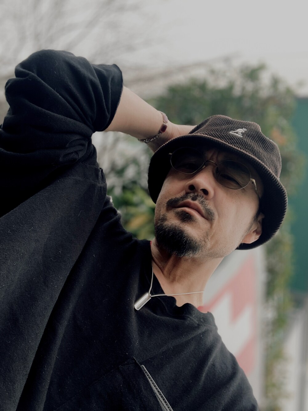 ブラック系のTシャツ/カットソー、ブラック系のスラックス、レッド系のスニーカーを着用したメンズの春コーディネートの5枚目の写真