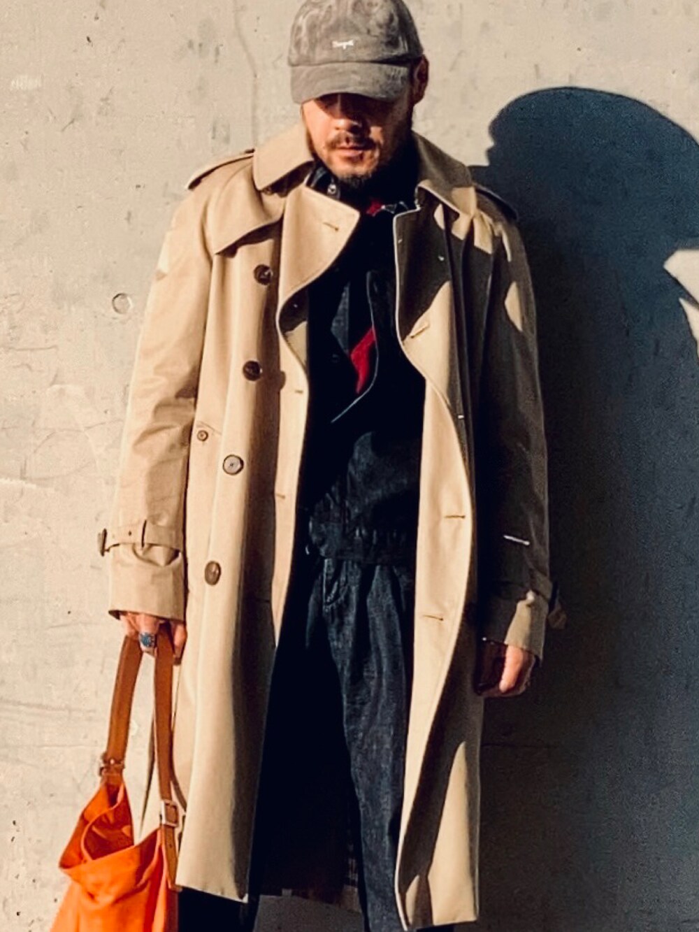 レッド系のニット/セーター、ブルー系のデニムジャケット、ベージュ系のトレンチコートを着用したメンズの冬コーディネートの2枚目の写真