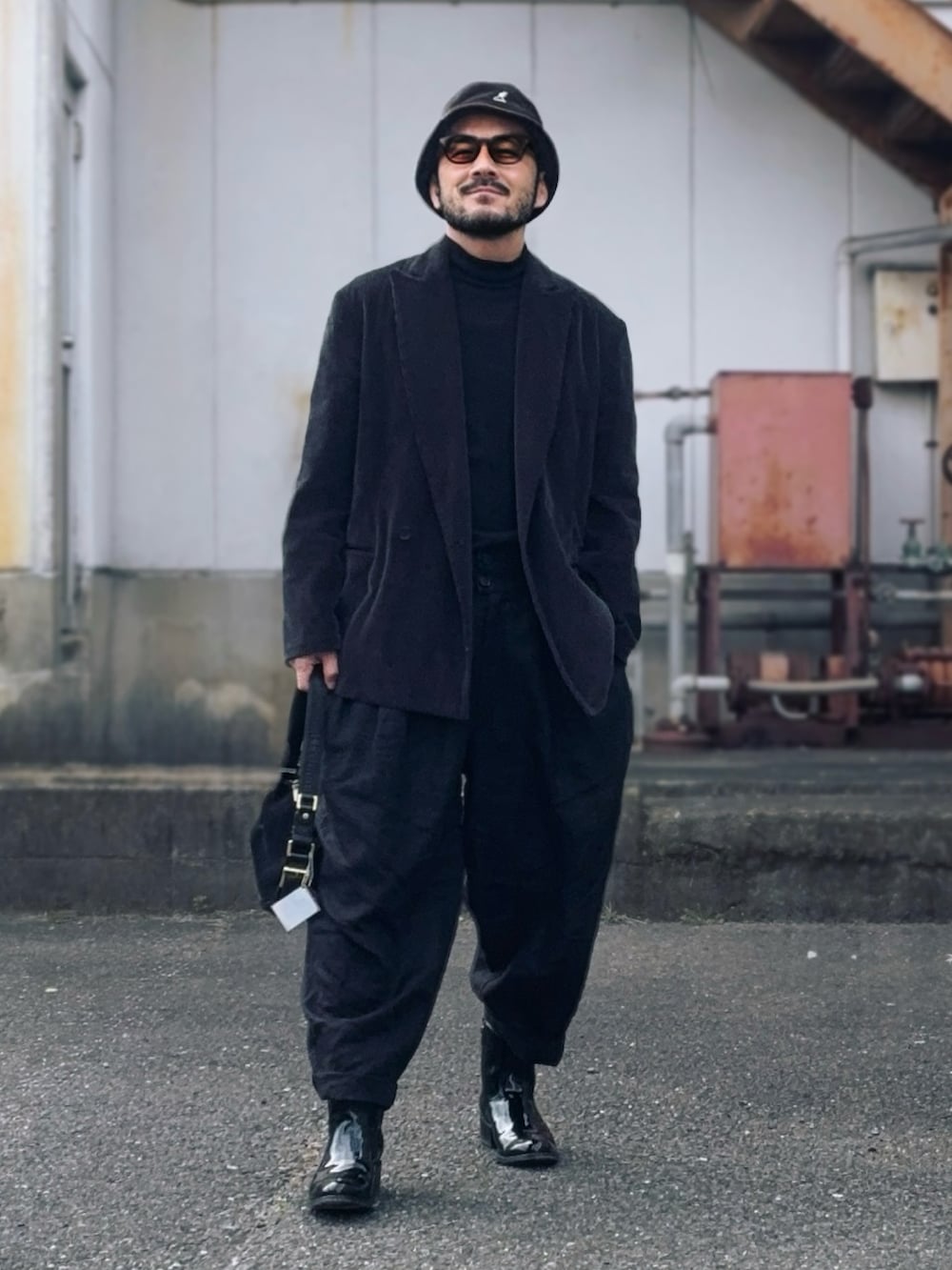 グレー系のテーラードジャケット、ブラック系のその他パンツ、ブラック系のハンドバッグを着用したメンズの冬コーディネートの2枚目の写真