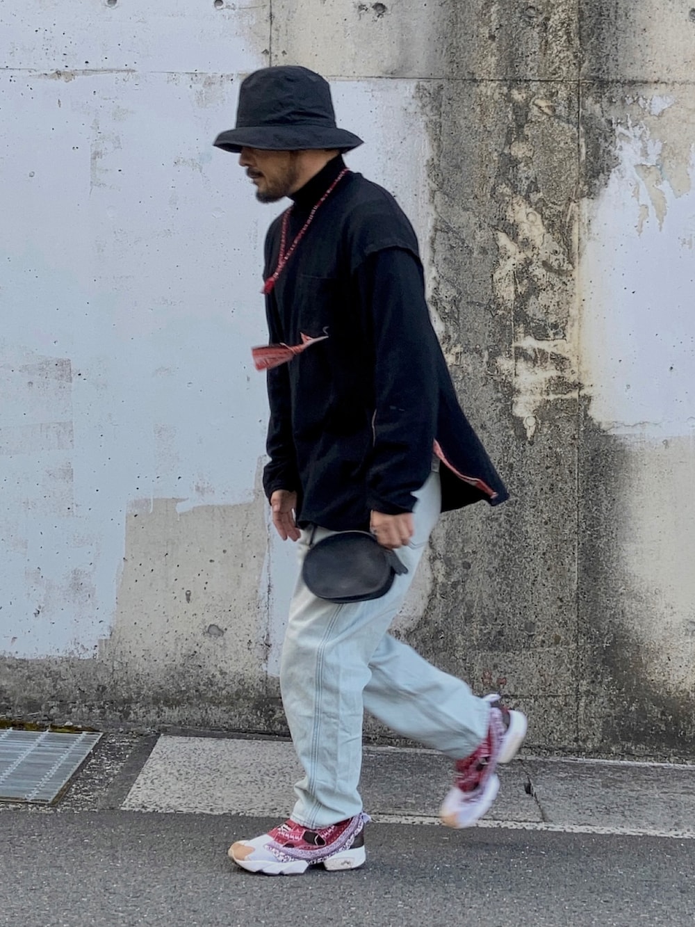 ブラック系のTシャツ/カットソー、ブルー系のデニムパンツ、レッド系のスニーカーを着用したメンズの冬コーディネートの2枚目の写真