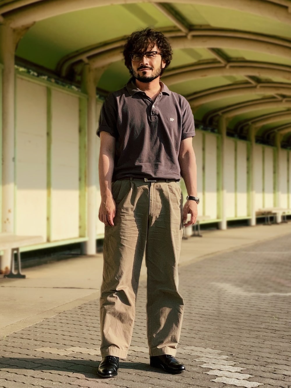 グレー系のポロシャツ、ベージュ系のチノパンツ、ブラック系のドレスシューズを着用したメンズの夏コーディネートの2枚目の写真