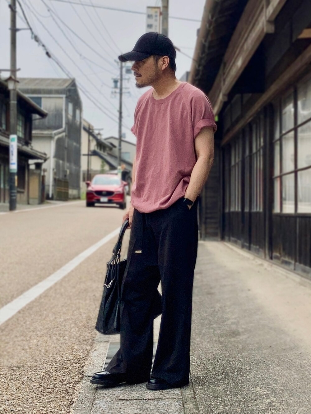 ピンク系のTシャツ/カットソー、ブラック系のスラックス、ブラック系のローファーを着用したメンズの夏コーディネートの3枚目の写真