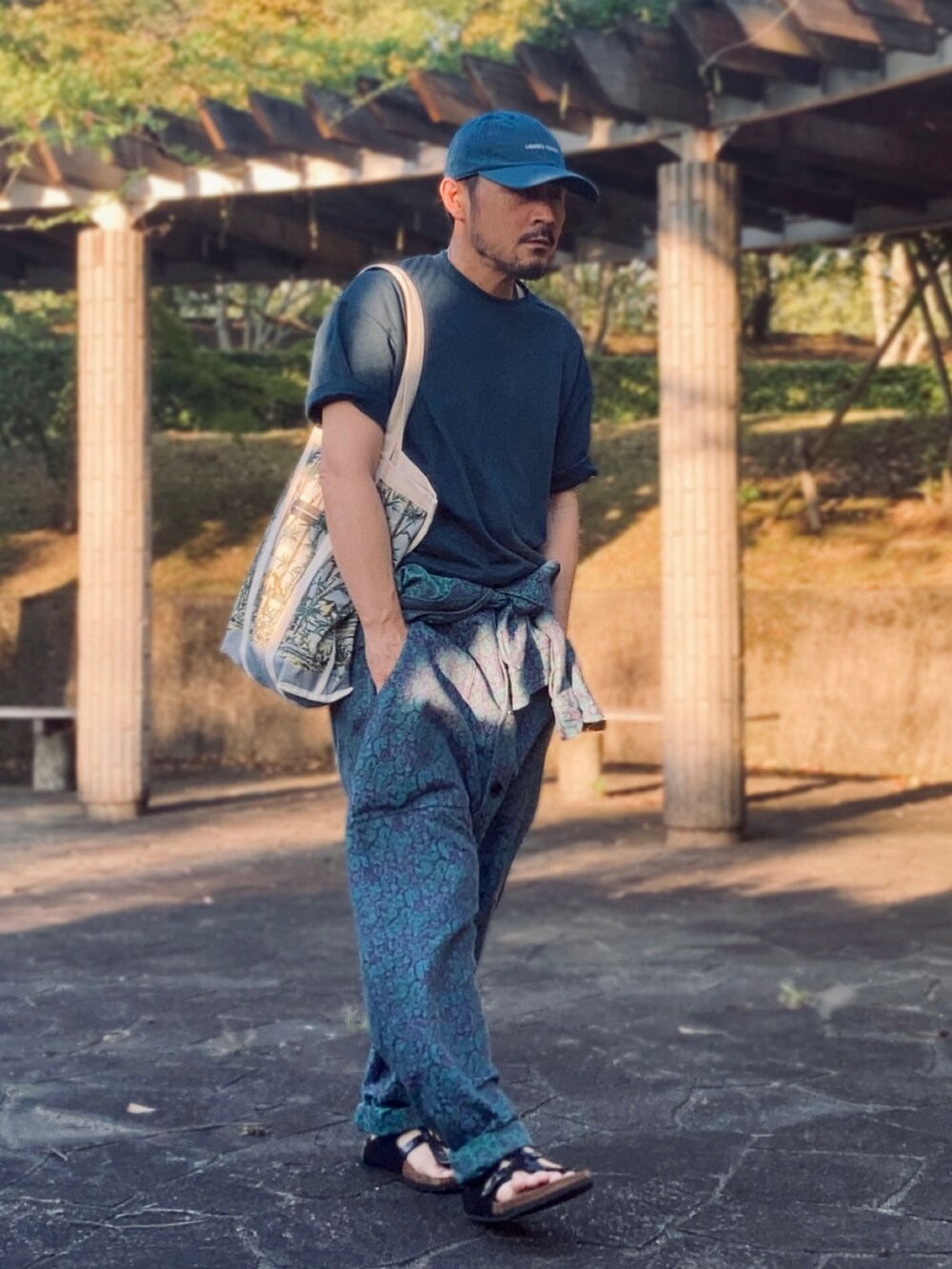 グリーン系のTシャツ/カットソー、ブルー系のつなぎ/オールインワン、ブラック系のサンダルを着用したメンズの夏コーディネートの2枚目の写真