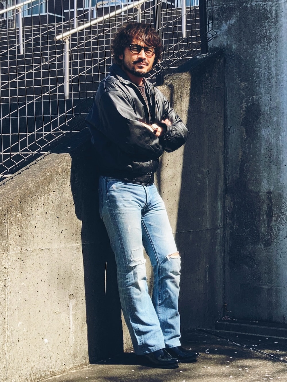 ブラック系のブルゾン、ブラック系のTシャツ/カットソー、ブルー系のデニムパンツを着用したメンズの春コーディネートの2枚目の写真