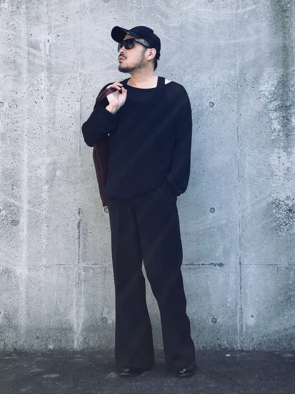 ブラック系のニット/セーター、ブラック系のスラックス、ブラック系のブーツを着用したメンズの春コーディネートの4枚目の写真