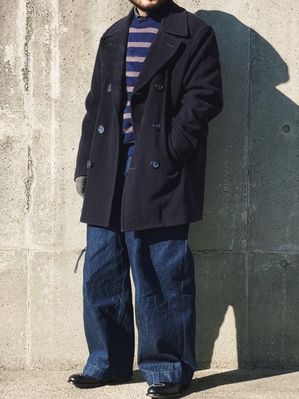 ブルー系のニット/セーター、ブルー系のピーコート、ブルー系のデニムパンツを着用したメンズの冬コーディネートの3枚目の写真