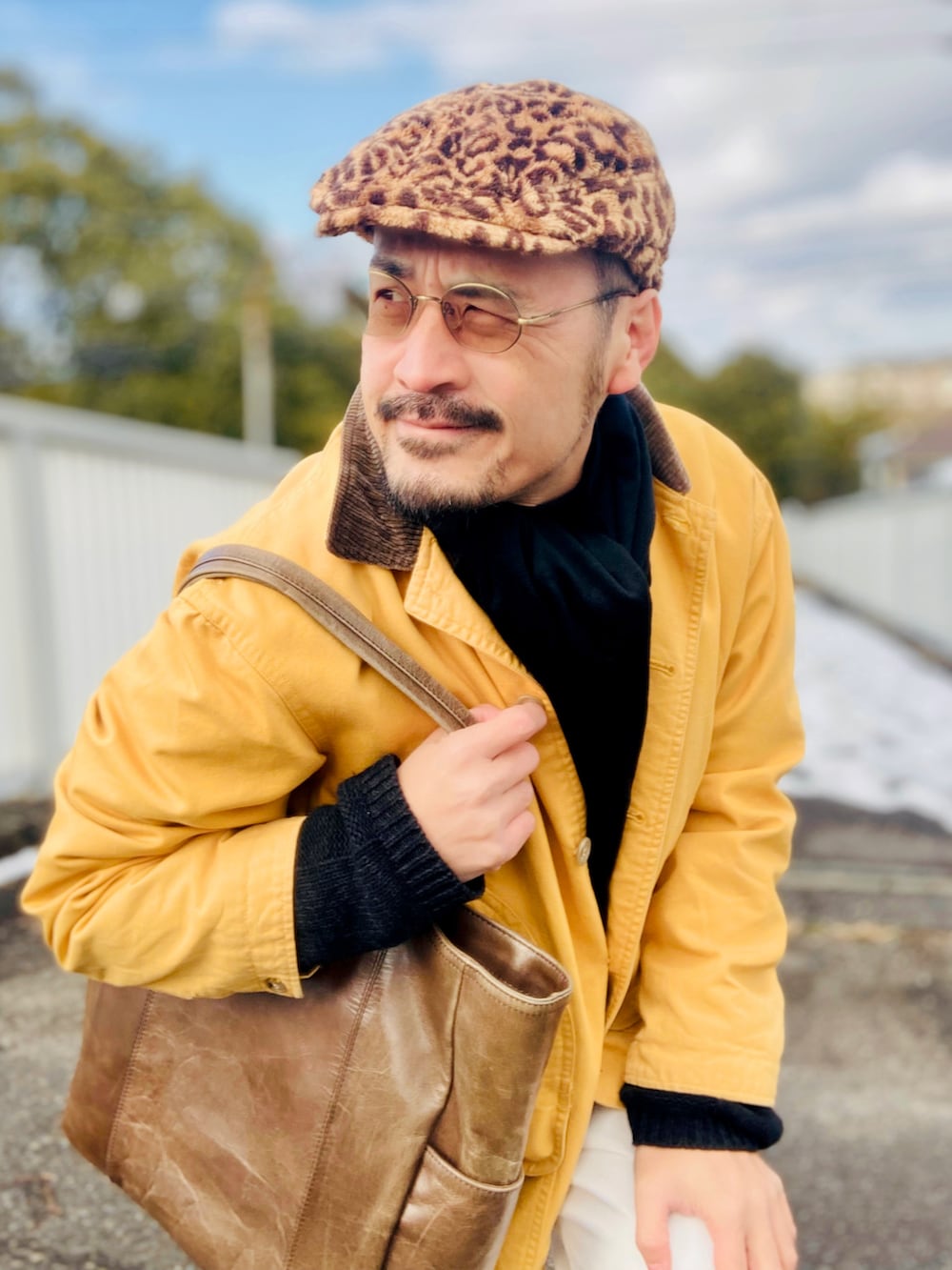 ブラック系のニット/セーター、イエロー系のカバーオール、ホワイト系のスラックスを着用したメンズの冬コーディネートの4枚目の写真