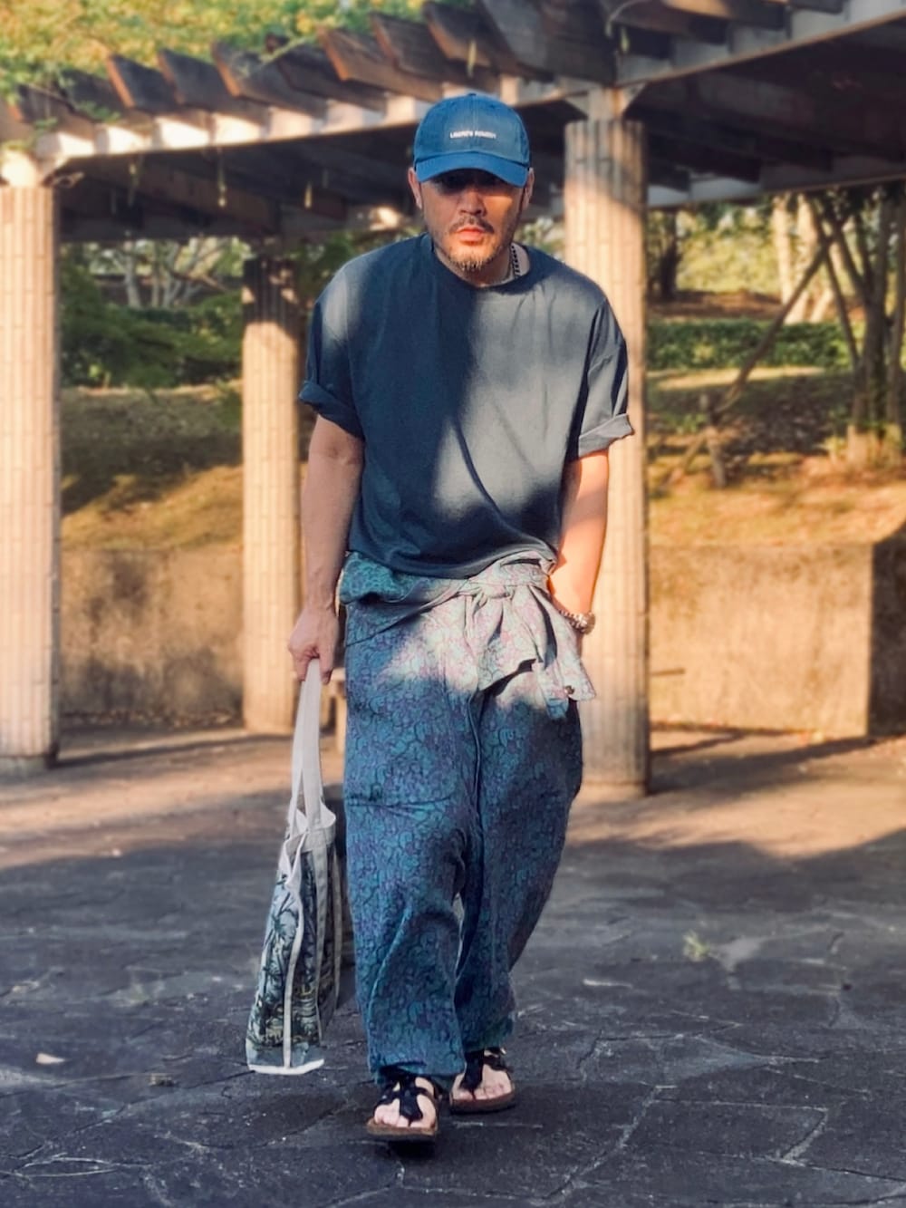 グリーン系のTシャツ/カットソー、ブルー系のつなぎ/オールインワン、ブラック系のサンダルを着用したメンズの夏コーディネートの3枚目の写真