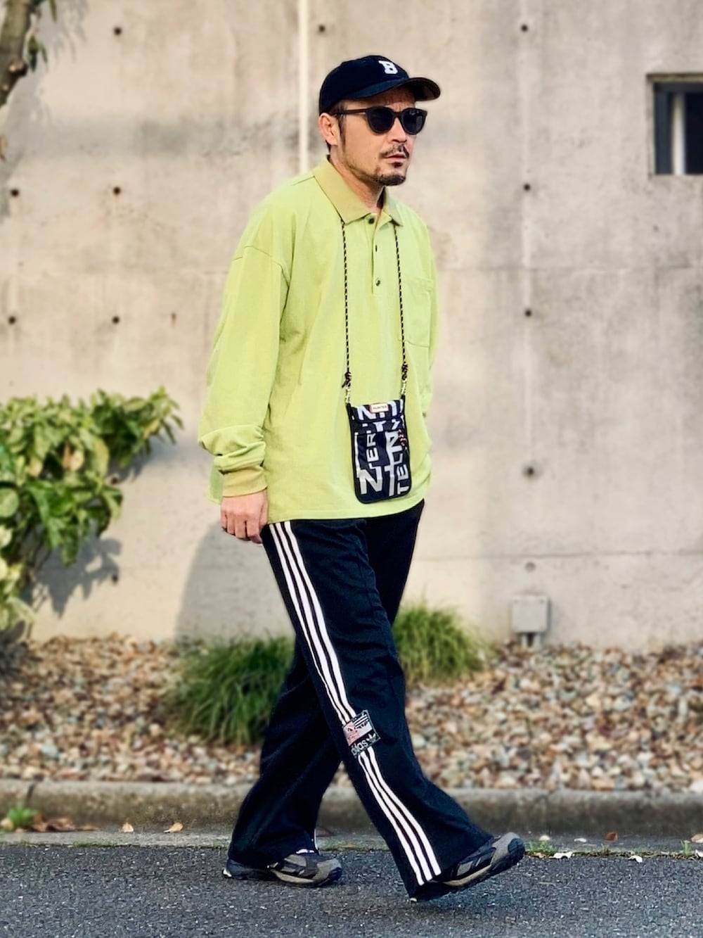 グリーン系のポロシャツ、ブラック系のスウェットパンツ、ブラック系のスニーカーを着用したメンズの春コーディネートの3枚目の写真