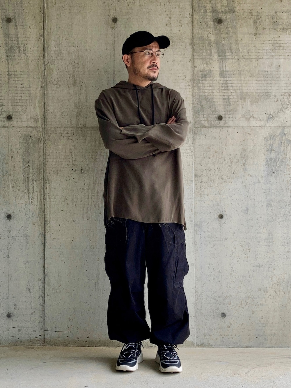 グレー系のパーカー、ブラック系のカーゴパンツ、ブラック系のスニーカーを着用したメンズの秋コーディネートの3枚目の写真