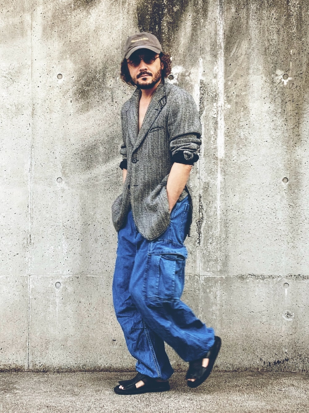 グレー系のテーラードジャケット、ブルー系のカーゴパンツ、ブラック系のサンダルを着用したメンズの秋コーディネートの3枚目の写真